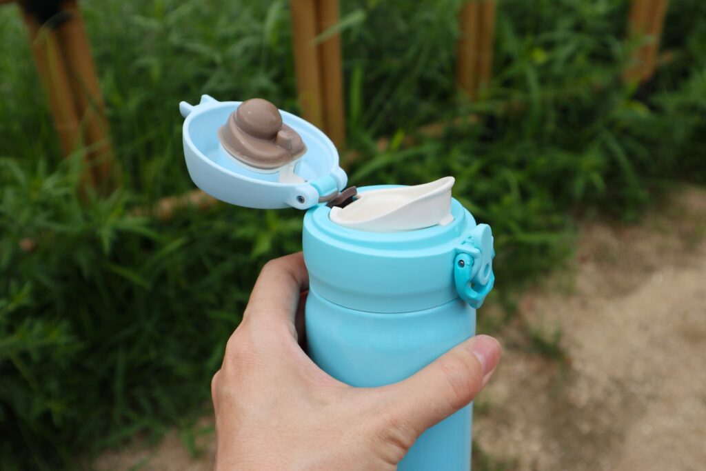 蓋が開いた水筒を持つ手