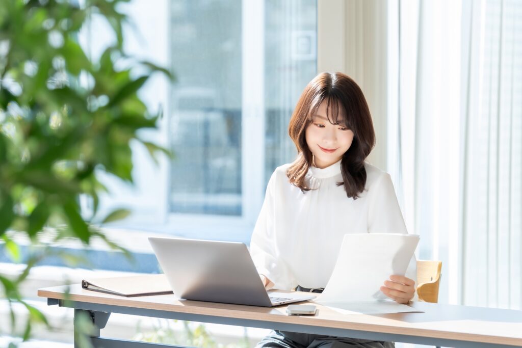 窓際でパソコン作業中の女性