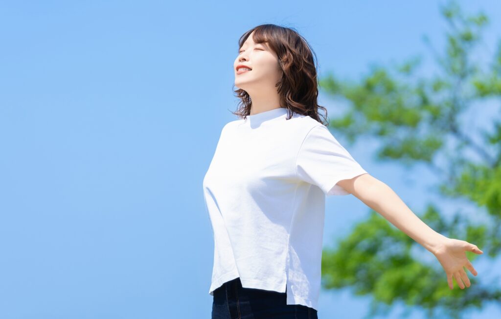 青空の下で深呼吸する女性 