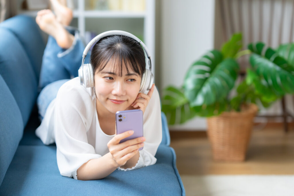 リビングでヘッドホンして音楽鑑賞する女性